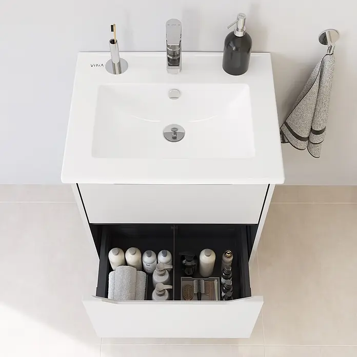 VitrA Integra Square Badmöbel-Set - Gesamtbreite Badmöbel: 60 cm, Hellgrau, Matt - Weißer Badschrank mit integriertem Waschbecken, Chromarmatur und geöffneter Schublade mit Badartikeln.