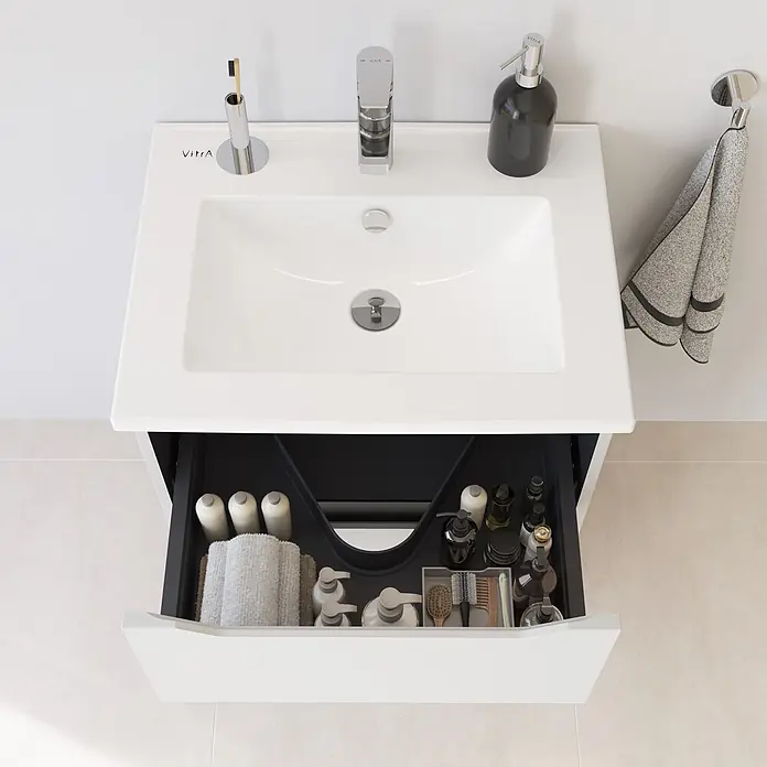 VitrA Integra Square Badmöbel-Set - Gesamtbreite Badmöbel: 60 cm, Hellgrau, Matt - Weißer VitrA Badezimmer-Waschtisch mit integriertem Waschbecken und Chromarmatur. Die offene Schublade zeigt organisierte Pflegeprodukte und ein Handtuch hängt daneben.