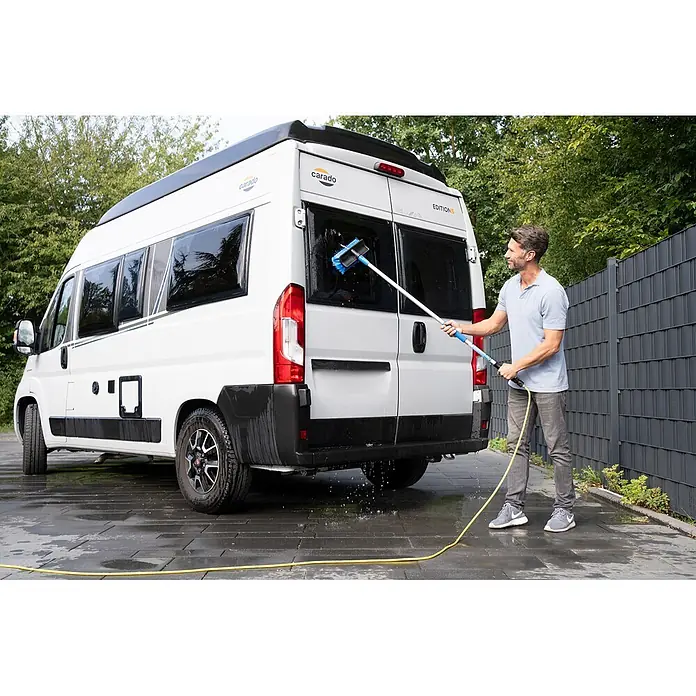 Unger HighFlow Reinigungs-Set Reinwasser 1,2m - 3 -tlg. - Mann reinigt einen weißen Camper mit einer langstieligen Waschbürste mit blauen Borsten und Schlauchanschluss.
