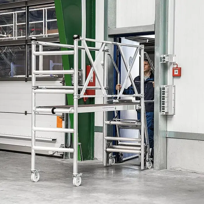 Munk Stehleiter Montageplattform mit Treppenzustieg 3m AH - Anzahl Tritte: 3 Stk., Arbeitshöhe: 3.000 m, Aluminium - Mobiles Aluminium-Rollgerüst, von einer Person zum Zugang durch eine Tür verwendet.