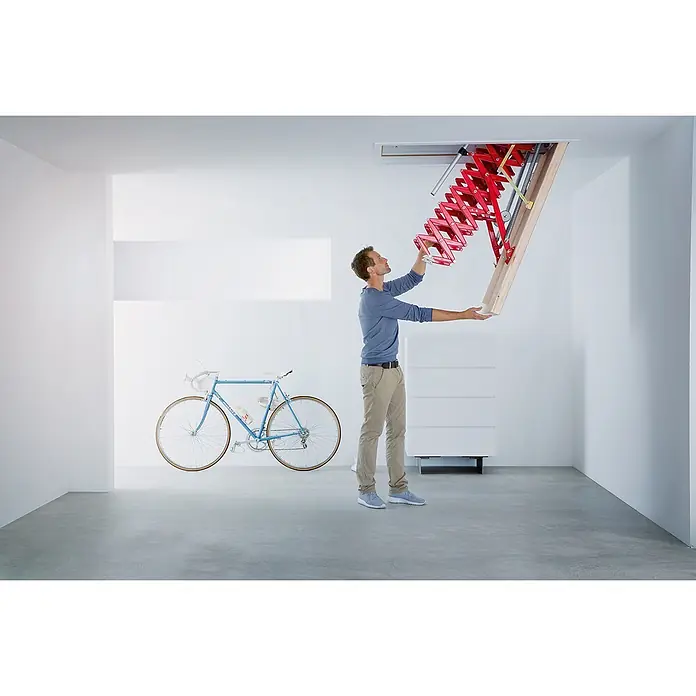 Roto Bodentreppe Scherentreppe Exklusiv 250cm max. Lichte Raumhöhe 120x60cm Rohbaumaß -  - Mann klappt eine rote Akkordeon-Bodentreppe aus der Deckenöffnung.