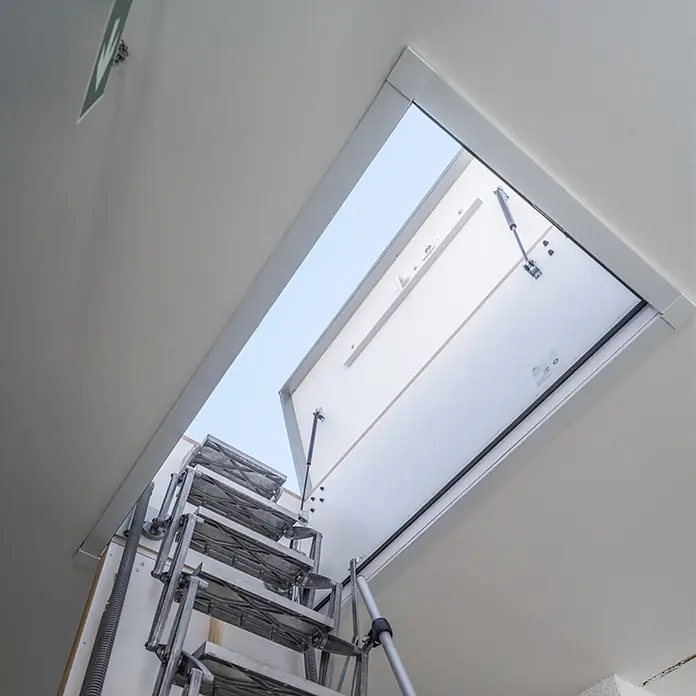Roto Bodentreppe Flachdachausstieg Exklusiv bis 309cm Raumhöhe 120x70cm Rohbaumaß -  - Ausklappbare Metall-Dachbodentreppe aus weißer Deckenluke, geöffnet zum Himmel.