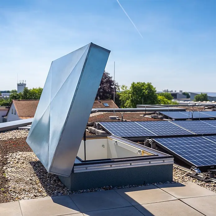 Roto Bodentreppe Flachdachausstieg Exklusiv bis 309cm Raumhöhe 120x70cm Rohbaumaß -  - Teilweise geöffnete metallene Dachlukenabdeckung auf Kiesdach neben Solarmodulen.