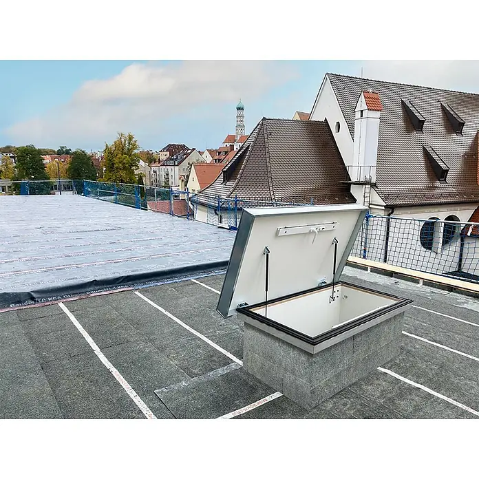 Roto Bodentreppe Flachdachausstieg Exklusiv bis 309cm Raumhöhe 120x70cm Rohbaumaß -  - Offene Dachluke auf einem Flachdach, mit weißem Innenraum und grauem Deckel, auf einem Betonsteinsockel montiert.