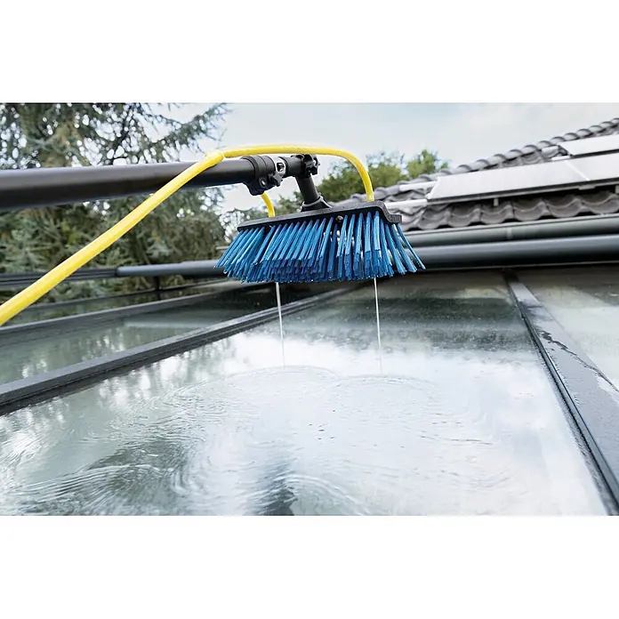 Unger HighFlow Reinigungs-Set Komplettstange - 3 -tlg. - Blaue Reinigungsbürste mit gelbem Schlauch an schwarzer Stange, reinigt eine Glasfläche. Wasser strömt aus den Borsten.