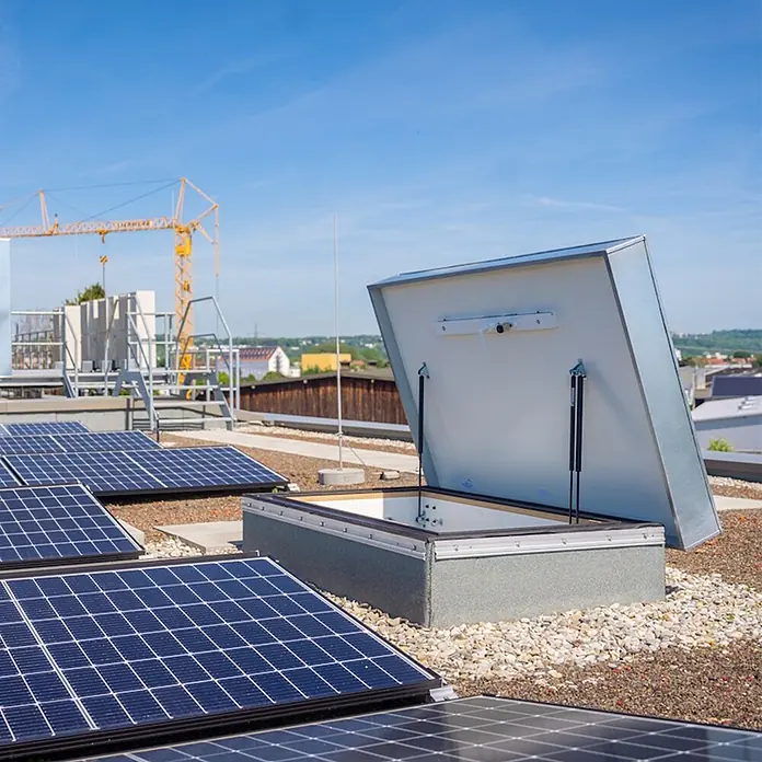 Roto Bodentreppe Flachdachausstieg Designo bis 280cm Raumhöhe 120x70cm Rohbaumaß -  - Offene graue Dachluke auf einem Kies-Flachdach, umgeben von Solarmodulen.
