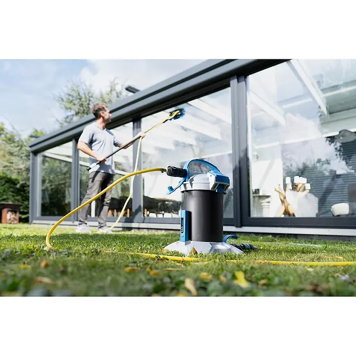 Unger HighFlow Filter Reinwasser - Passend für: Unger HighFlow Reinigungs-Set Komplettstange - Wasserfiltersystem, mit gelbem Schlauch an einen Mann angeschlossen, der ein Glasgewächshaus reinigt.