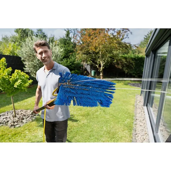 Unger HighFlow Reinigungs-Set Komplettstange - 3 -tlg. - Mann reinigt Fenster mit einer langstieligen Bürste mit blauen Borsten und integriertem Wasserspray.