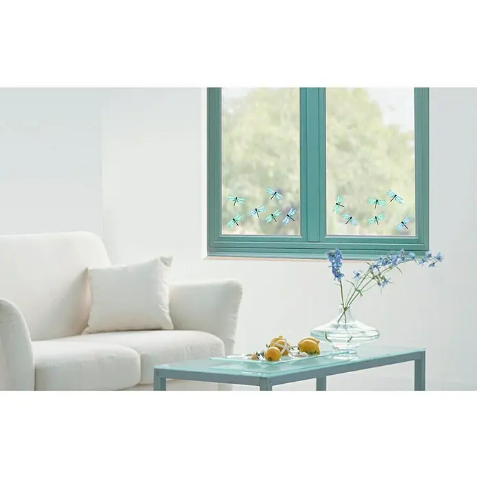 Vinilo de pared cristal - 21 x 29,7 cm, Azul, Plástico - Primer plano de una ventana con adhesivos de libélulas azules en una habitación luminosa, con sofá y mesa.