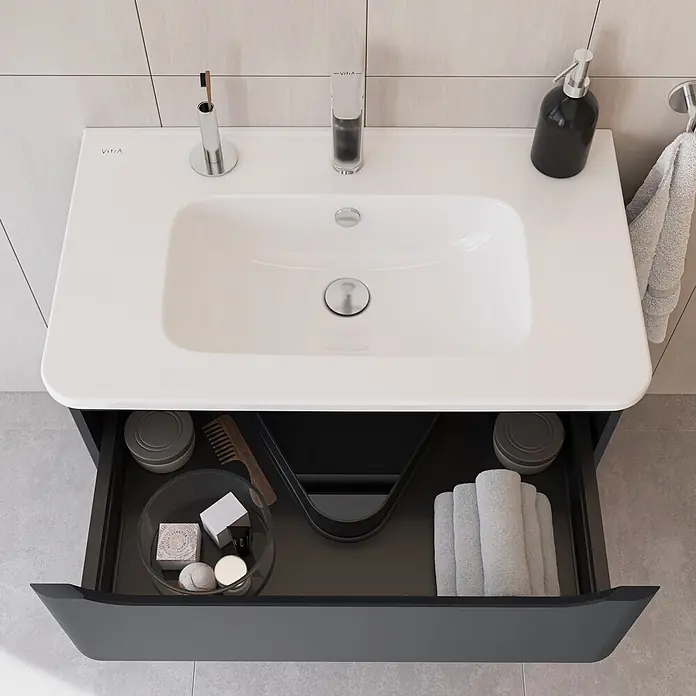 VitrA Integra Round Badmöbel-Set - Gesamtbreite Badmöbel: 80 cm, Graphit, Matt - Moderner weißer Waschtisch mit dunkelgrauem Unterschrank; offene Schublade zeigt Toilettenartikel und Handtücher.