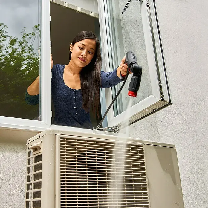 Bosch Hochdruckreiniger EasyAquatak 100 - 100 bar, 1.100 W, Fördermenge: 270 l/h - Frau reinigt Klimaanlage mit Hochdruckreiniger. Das Gerät sorgt für Sauberkeit und effiziente Kühlleistung.