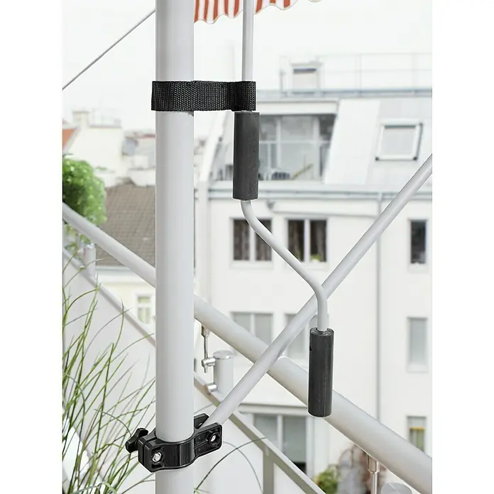 Sunfun Klemmmarkise - Orange/Weiß, Breite: 3 m, Ausfall: 1,5 m - Nahaufnahme einer weißen Wäschespinne mit schwarzem Gurt und Halterung auf einem Balkon, die Funktionalität und Design vereint.