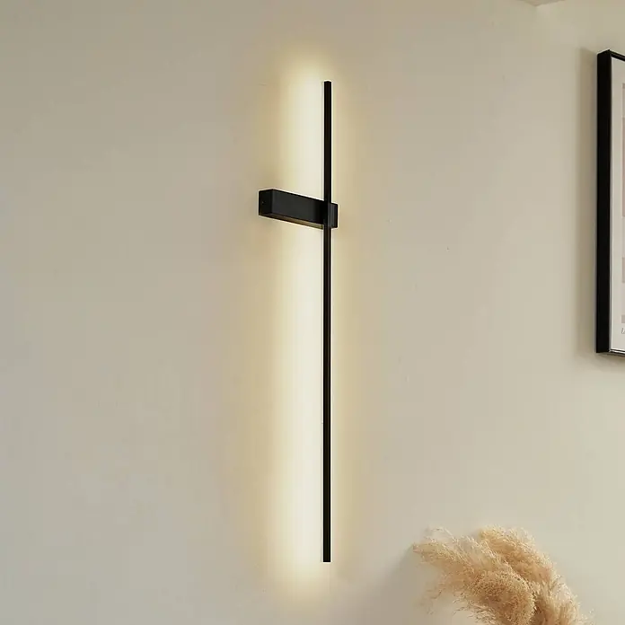 Lindby Wandleuchte Natsumi - schwarz - Schwarze, kreuzförmige LED-Wandleuchte, vertikal an einer Wand montiert, die warmes Licht nach oben und unten abgibt.