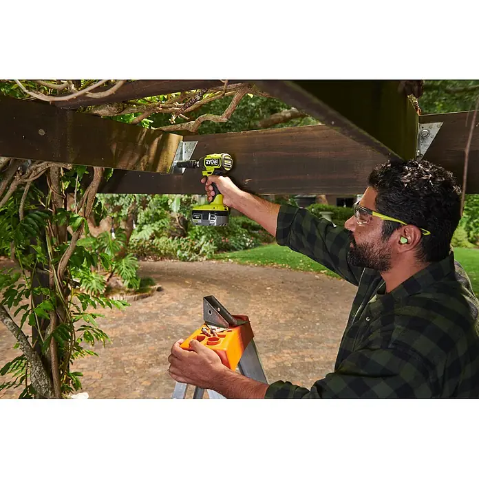 Ryobi ONE+HP Akku-Schlagschrauber RID18X1-0 - 18 V, Ohne Akku, 320 Nm - Grüne Ryobi Akku-Bohrmaschine befestigt eine Metallhalterung an einem Holzbalken.