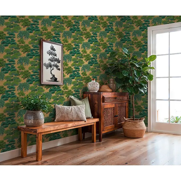 A.S. Création Cuba 2 Vliestapete Natur - Gold-Grün, Floral, 10,05 x 0,53 m - Grüne Laubtapete auf goldenem Hintergrund, verwendet in einem Raum mit Holzmöbeln und Pflanzen.