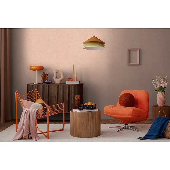 A.S. Création Nordic Feeling Vliestapete Uni - Rosa, Uni, 10,05 x 0,53 m - Oranger Metall-Drahtsessel mit Kissen und rosa Decke in einem gemütlichen Wohnzimmer.