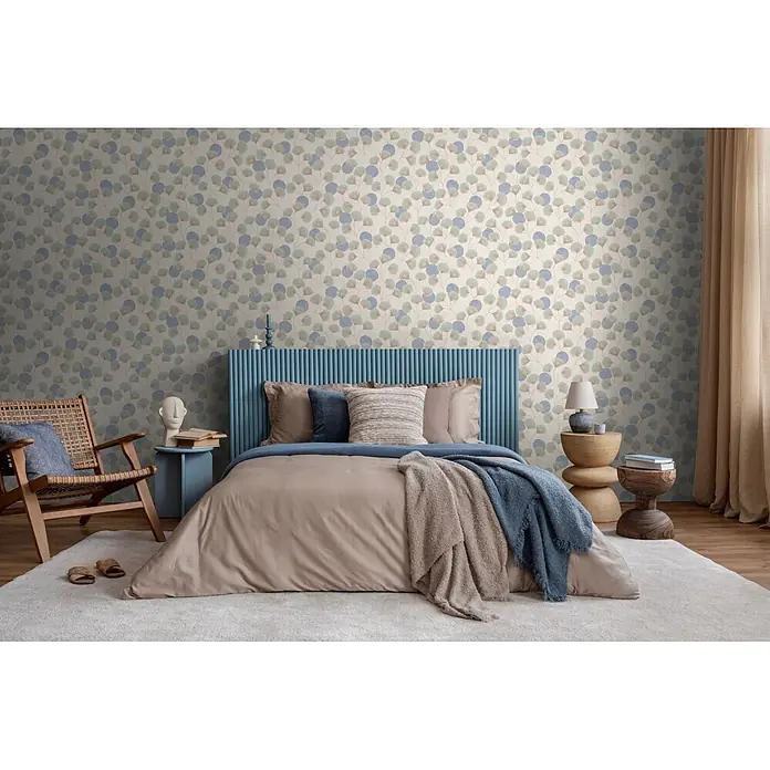 A.S. Création Nordic Feeling Vliestapete Blätter I - Grau-Grün, Floral, 10,05 x 0,53 m - Tapete mit blauem und beigem Kreismuster aus Blättern auf hellem Hintergrund in einem modernen Schlafzimmer.