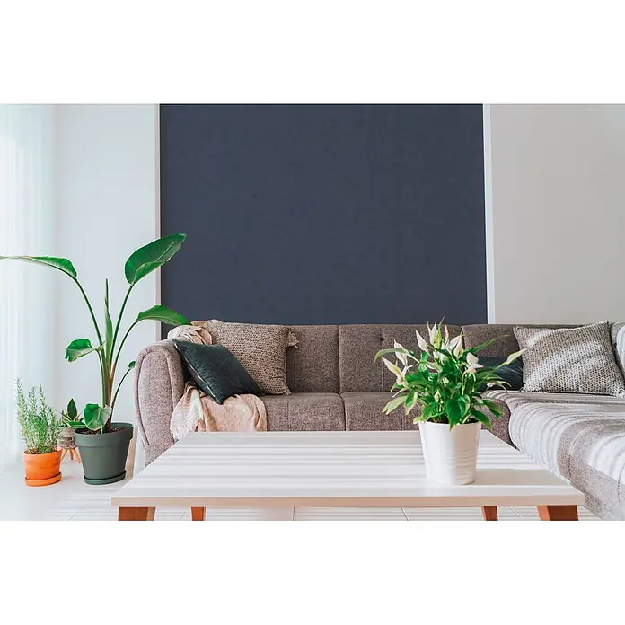 A.S. Création Nordic Feeling Vliestapete Uni - Blau, Uni, 10,05 x 0,53 m - Gemütliches Wohnzimmer mit grauem Ecksofa, weißem Couchtisch und verschiedenen Grünpflanzen, darunter eine große Strelitzie.