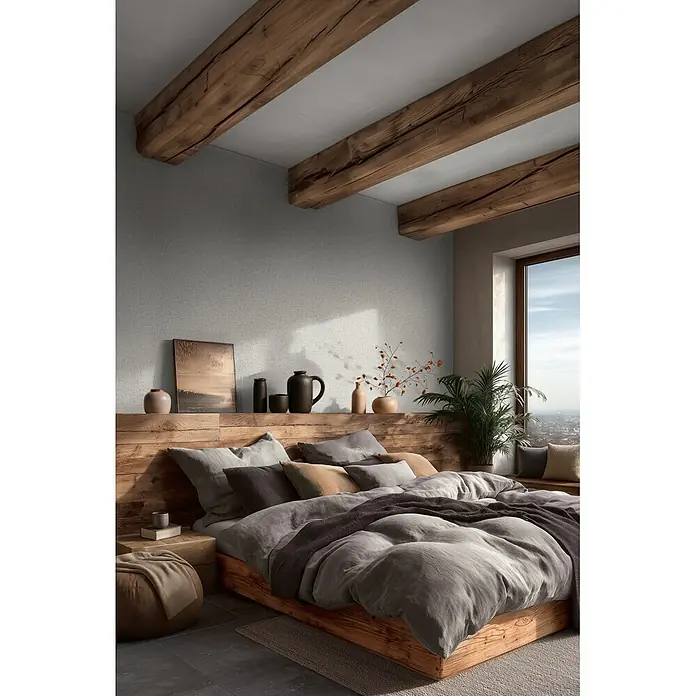 A.S. Création Metropolitan Stories Vibes & Styles Vliestapete Rattan - Grau-Weiß, Uni, 10,05 x 0,53 m - Rustikales Holzbettgestell und Kopfteil in einem gemütlichen Schlafzimmer mit weicher grauer Bettwäsche und mehreren Kissen.