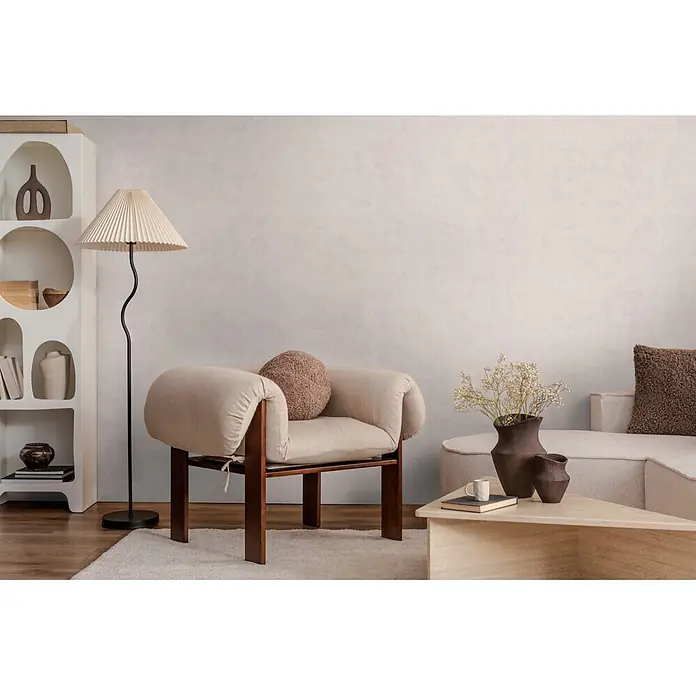 A.S. Création Nordic Feeling Vliestapete Uni - Grau, Uni, 10,05 x 0,53 m - Ein modernes Wohnzimmer mit einem hellbeigen Sessel mit Holzrahmen, einer Plissee-Stehlampe und einem Ecksofa in neutralen Farben.