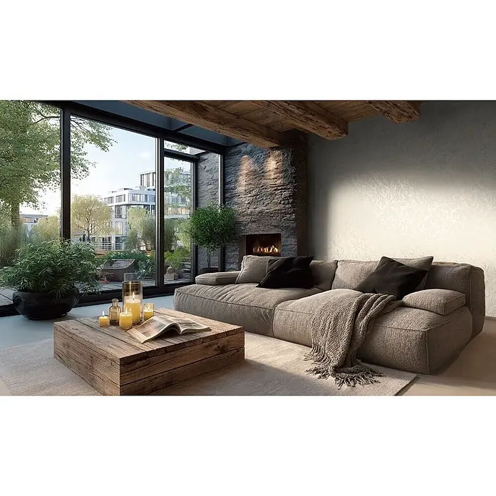 A.S. Création Metropolitan Stories Vibes & Styles Vliestapete Gräser I - Creme, Floral, 10,05 x 0,53 m - Ein geräumiges graues Stoff-Ecksofa mit gestricktem Überwurf und schwarzen Kissen in einem gemütlichen Wohnzimmer mit rustikalem Couchtisch aus Holz.