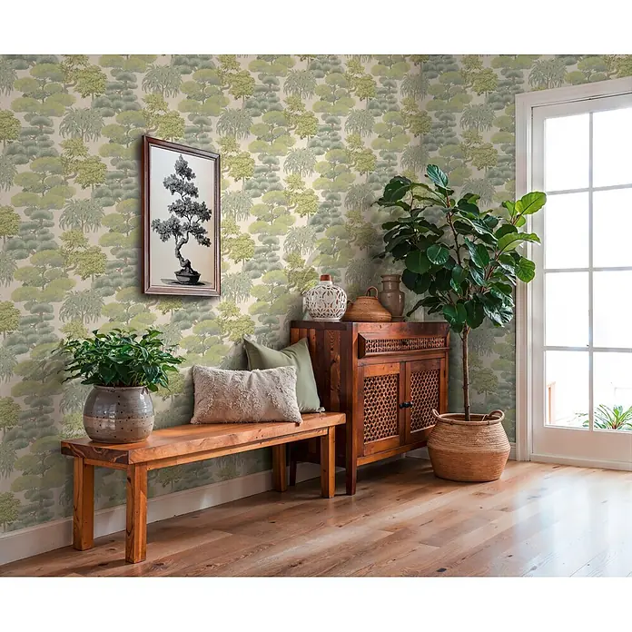 A.S. Création Cuba 2 Vliestapete Natur - Hellgrün-Creme, Floral, 10,05 x 0,53 m - Tapete mit sich wiederholendem Muster aus stilisierten grünen Bäumen in einem Zimmer mit Holzmöbeln und Pflanzen.