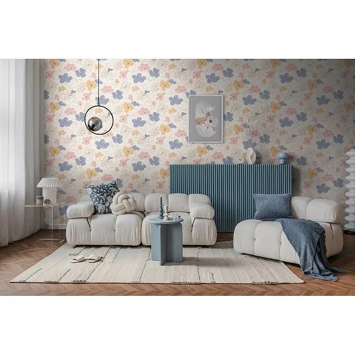 A.S. Création Nordic Feeling Vliestapete Floral - Grau-Gelb, Floral, 10,05 x 0,53 m - Florale Tapete in Rosa, Blau und Gelb schmückt eine Wohnzimmerwand hinter einem Sofa.