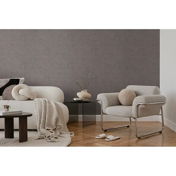 A.S. Création Nordic Feeling Vliestapete Uni I - Grau, Uni, 10,05 x 0,53 m - Modernes Wohnzimmer mit grauer Wand, weißem Bouclé-Sofa, hellgrauem Sessel und Holzboden, minimalistisch eingerichtet.
