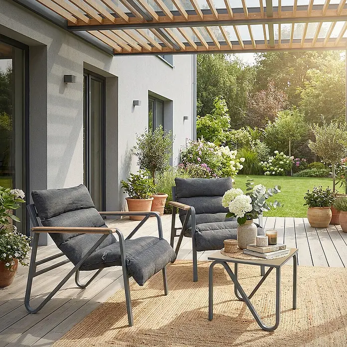 ML-Design Gartenstuhl-Set mit Tisch - 3 Stk., Stahl pulverbeschichtet, kationisches Polyestergewebe, Schaumstoff, Keramikglas, Anthrazit, Braun - Zwei moderne graue Loungesessel mit Holzarmlehnen und ein passender Beistelltisch auf einer Terrasse mit Jute-Teppich, vor einem Garten.