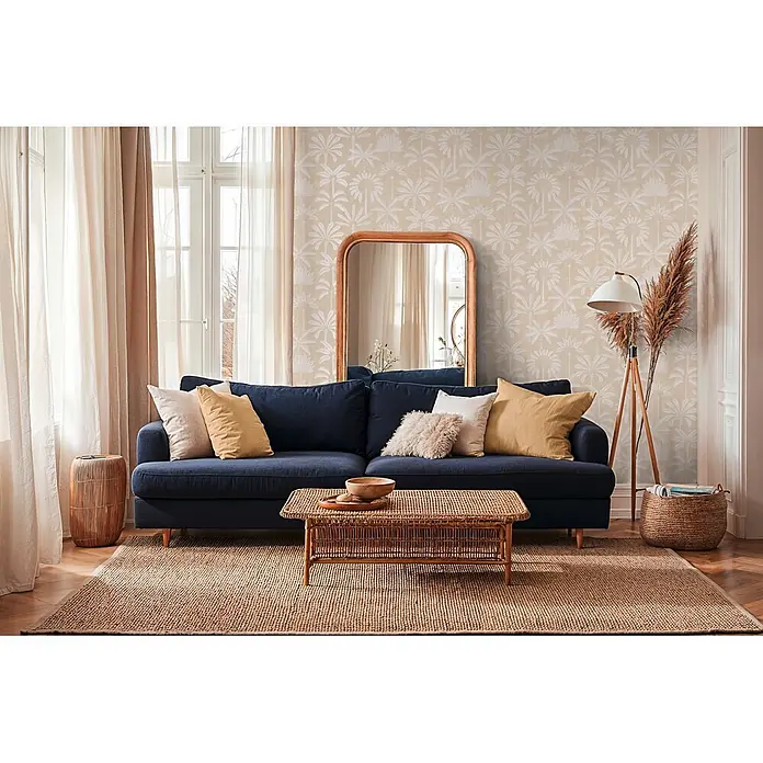A.S. Création Cuba 2 Vliestapete Palmen II - Beige-Creme, Floral, 10,05 x 0,53 m - Marineblaues Sofa mit Kissen in einem gemütlichen Wohnzimmer, mit einem Rattan-Couchtisch und Naturteppich.