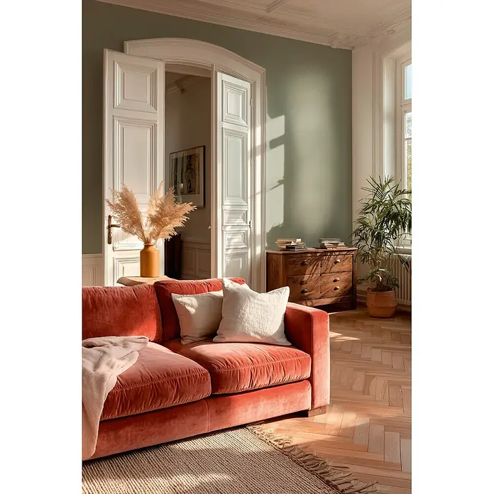 A.S. Création Metropolitan Stories Vibes & Styles Vliestapete Textil - Grün, Uni, 10,05 x 0,53 m - Terracotta-Samtsofa mit cremefarbenen Kissen in einem sonnigen Wohnzimmer.