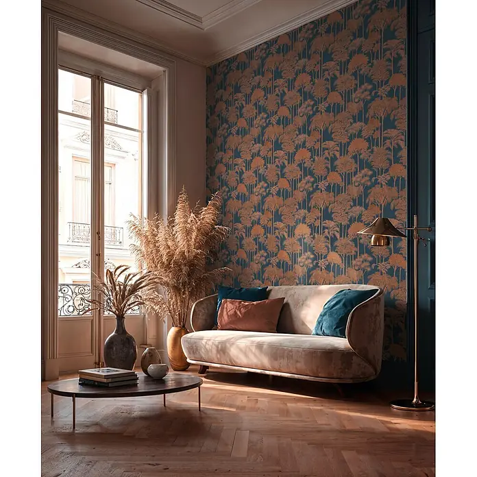 A.S. Création Cuba 2 Vliestapete Wald - Blau-Braun, Floral, 10,05 x 0,53 m - Gebogenes beiges Samtsofa mit Zierkissen in einem stilvollen Wohnzimmer.