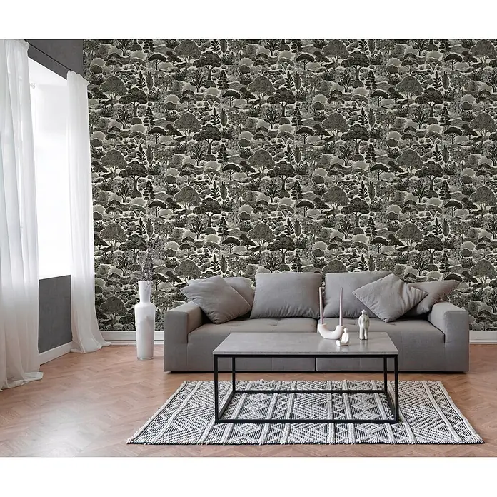 A.S. Création Pintwalls 3 Vliestapete Natur - Grau-Schwarz, Floral, 10,05 x 0,53 m - Schwarz-weiß-Tapete mit Waldmuster an einer Wohnzimmerwand hinter einem grauen Sofa.