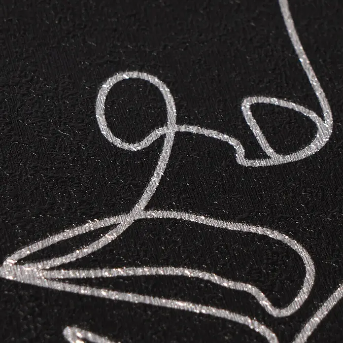 A.S. Création Pintwalls 3 Vliestapete Gesichter - Schwarz-Silber, Grafisch, 10,05 x 0,53 m - Nahaufnahme von schwarzem strukturiertem Material mit glänzenden silbernen Metalllinien, die ein Design bilden.
