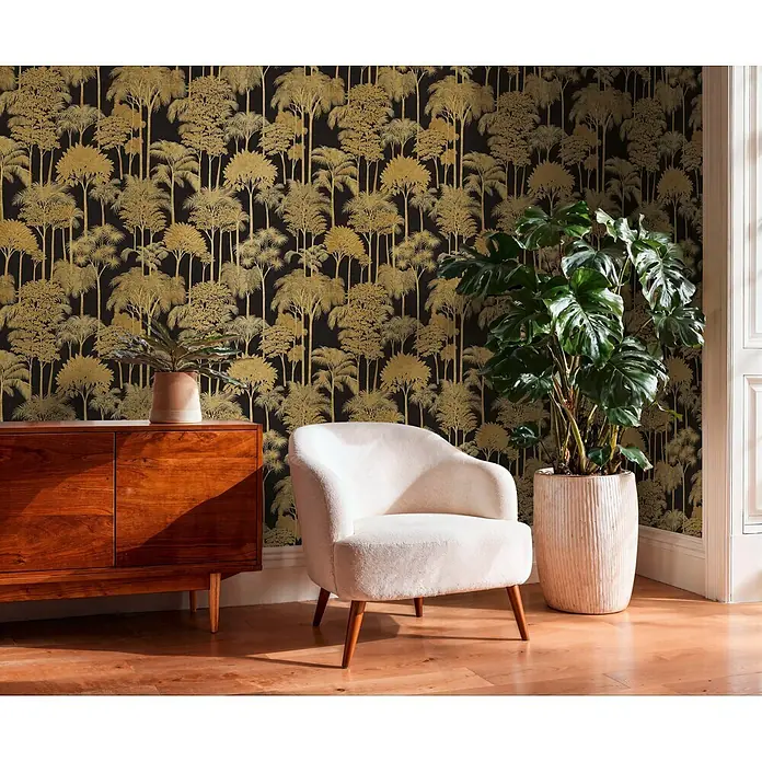 A.S. Création Cuba 2 Vliestapete Wald - Schwarz-Gold, Floral, 10,05 x 0,53 m - Schwarze Tapete mit aufwendigen goldenen Baum- und Palmenmustern, verwendet in einem stilvollen Raum mit Holzmöbeln und Pflanzen.