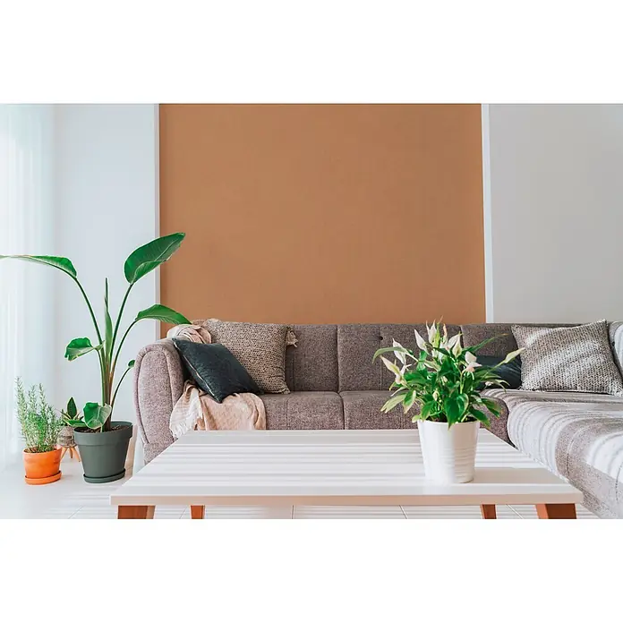 A.S. Création Cuba 2 Vliestapete Uni - Karamell, Uni, 10,05 x 0,53 m - Texturierte braune Akzentwand hinter einem grauen Sofa in einem modernen Wohnzimmer.