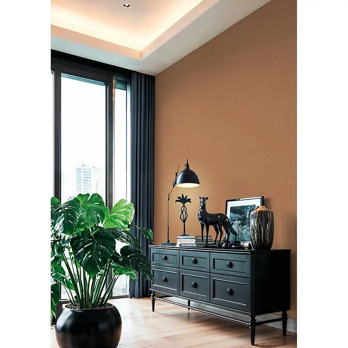 A.S. Création Cuba 2 Vliestapete Uni - Karamell, Uni, 10,05 x 0,53 m - Eine schwarze Holzkommode mit sechs Schubladen, dekoriert mit einer Lampe und Ziergegenständen in einem modernen Wohnzimmer.
