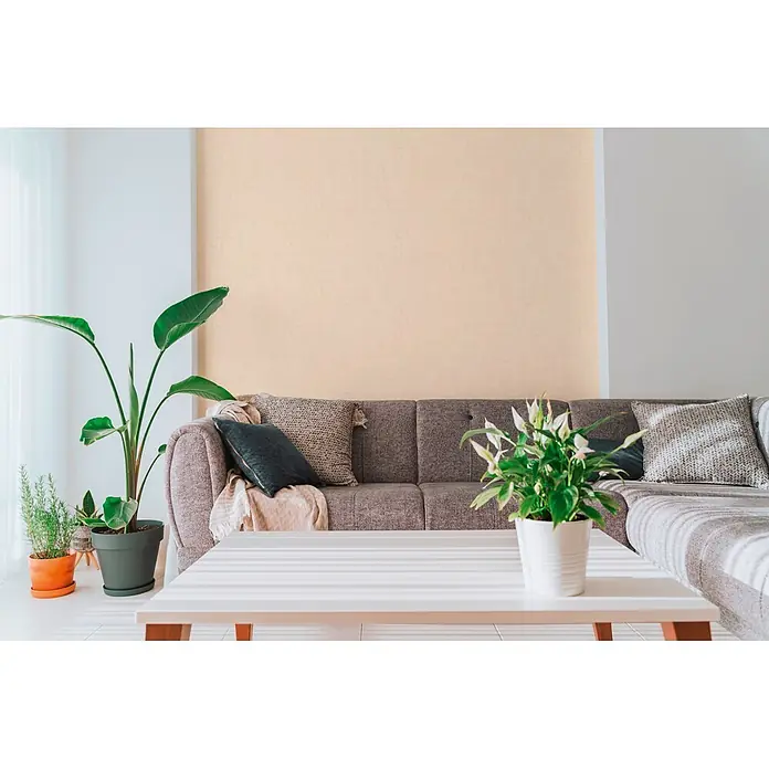 A.S. Création Cuba 2 Vliestapete Uni - Beige, Uni, 10,05 x 0,53 m - Strukturierte, hellbeige Tapete an einer Akzentwand im Wohnzimmer hinter einem Sofa.