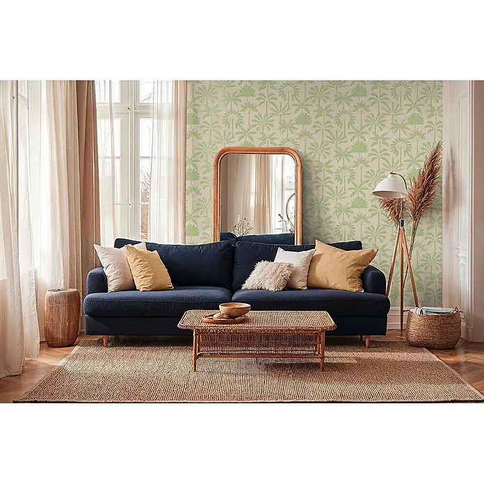 A.S. Création Cuba 2 Vliestapete Palmen II - Beige-Grün, Floral, 10,05 x 0,53 m - Marineblaues Stoffsofa mit Kissen in einem Wohnzimmer, auf einem strukturierten Teppich platziert.