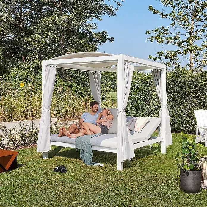 Home Deluxe Gartenliege LYON - B x T: 188 x 208 cm, Weiß, Grau, Polyester - Weißes Outdoor-Tagesbett mit grauen Kissen und Überdachung, von einem Paar im Garten genutzt.