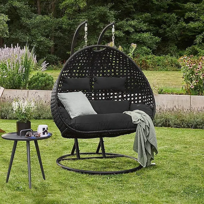 Home Deluxe Hängesessel TWIN - Kunststoff, Schwarz - Schwarzer geflochtener Doppelschaukelstuhl mit schwarzen Kissen, hellgrauem Kissen und grünem Überwurf.