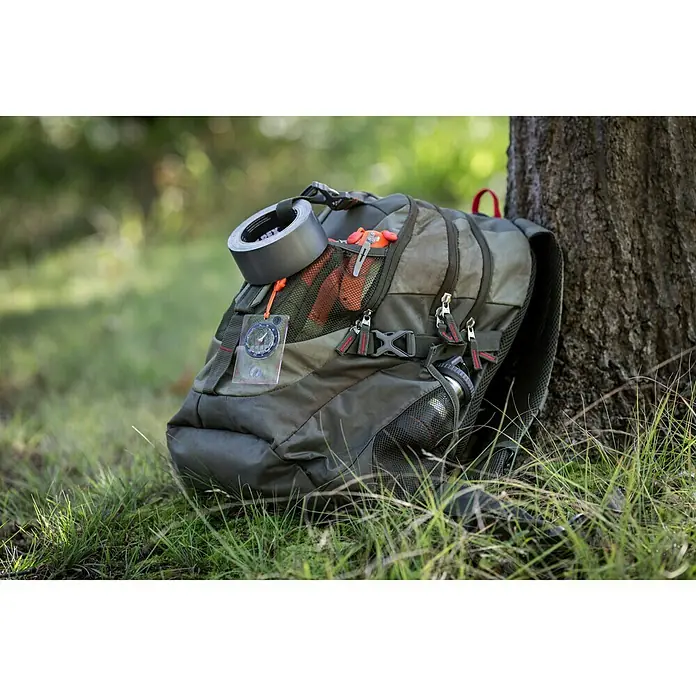 T-Rex Gewebeband - Schwarz, L x B: 9,1 m x 25 mm - Ein olivgrüner Rucksack mit Kompass, Klebeband und Werkzeug vor einem Baum.
