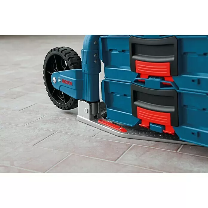 Bosch Professional Carretilla plegable Alu-Caddy - Específico para: Maletín de herramientas Bosch Professional L-BOXX, ABS - Primer plano de un carro de herramientas azul Bosch con rueda negra y pestillos rojos sobre suelo de baldosas.