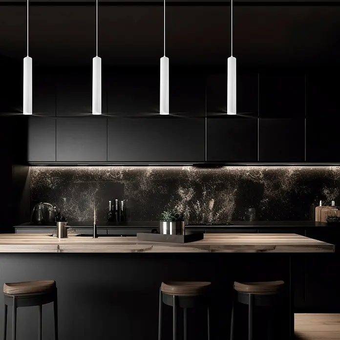 Alemar Lámpara colgante Antia - 50 W, Blanco, GU10 - Cuatro lámparas colgantes cilíndricas blancas cuelgan sobre una moderna isla de cocina oscura con encimera de madera.