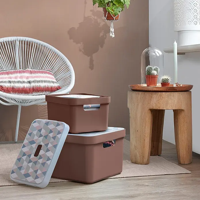 Sunware Sigma home Aufbewahrungsbox - L x B x H: 35 x 24,6 x 18,3 cm, Kunststoff, Schoko - Zwei braune Aufbewahrungsboxen, eine mit gemustertem Deckel, gestapelt in einem Wohnzimmer.
