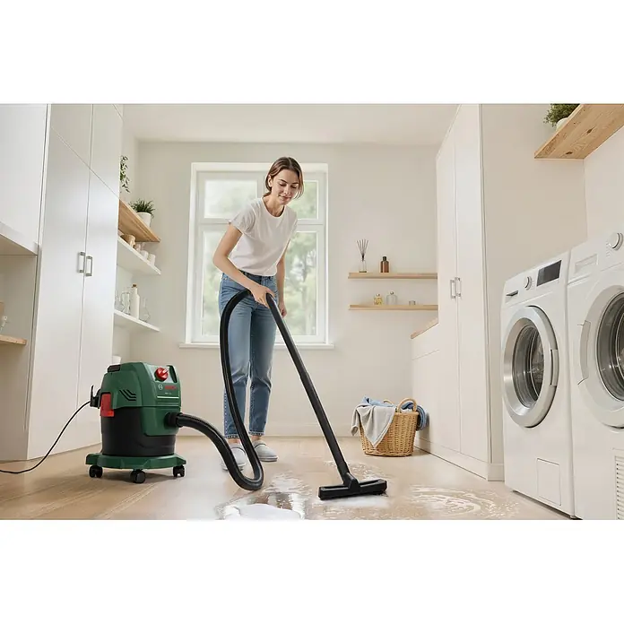Bosch Elektro-Nass- & Trockensauger PAS 15-200 - 1.200 W, Behältervolumen: 15 l - Frau nutzt grünen und schwarzen Bosch Nass-/Trockensauger zur Reinigung einer Seifenlache auf Holzboden.