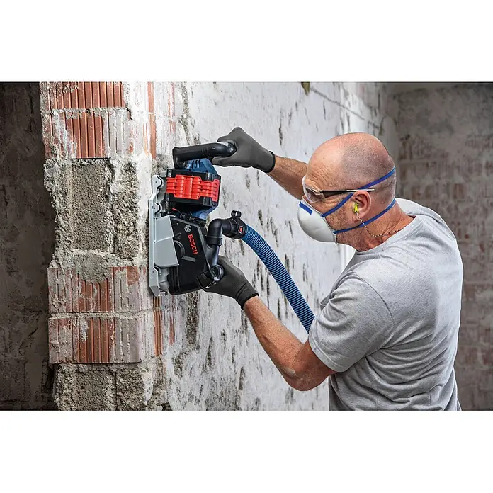 Bosch Professional AMPShare 18V Akku-Mauernutfräse GNF18V-40 - 18 V, Ohne Akku, Durchmesser Schleifscheibe: 150 mm - Arbeiter nutzt blaue Bosch Mauernutfräse mit Staubabsaugung an Ziegelwand.