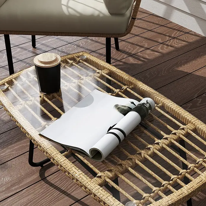 Outsunny Garten-Beistelltisch - L x B x H: 90 x 50 x 45 cm, Stahl, PE-Rattan, gehärtetes Glas, Rechteckig, Naturholz - Ein Rattan-Couchtisch mit Glasplatte auf einer Holzterrasse, mit Magazin und schwarzem Behälter, neben einem Outdoor-Stuhl.