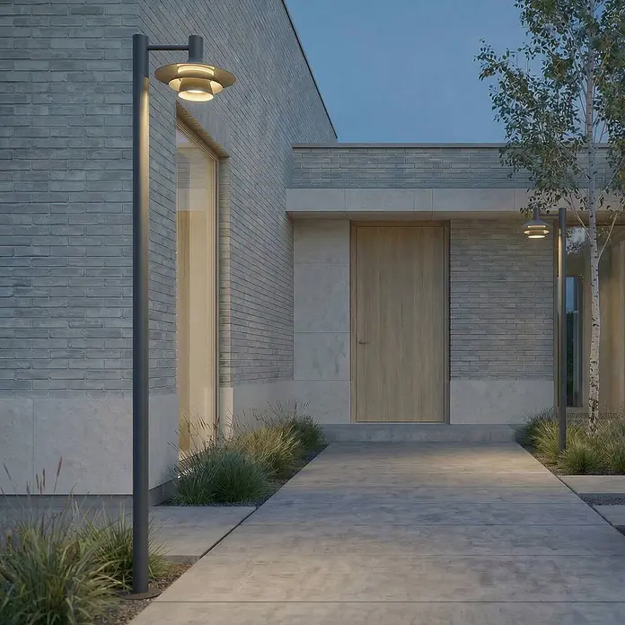 Lucande LED Gartenlaterne für draußen in anthrazit, weiß, Mastleuchte -  - Dunkelgraue Pollerleuchten mit modernem Schichtdesign beleuchten einen gepflasterten Weg zu einem modernen Gebäudezugang in der Dämmerung.