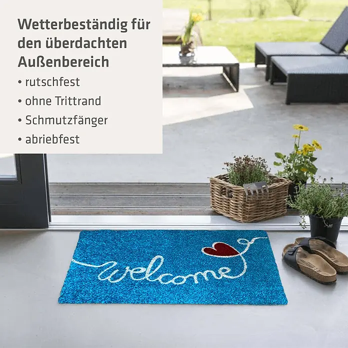 Akzente Fußmatte Listen - Mehrfarbig, Motiv / Muster|Schriftzug - Blaue Fußmatte mit „Welcome“-Schriftzug und rotem Herz, an einem überdachten Eingangsbereich.